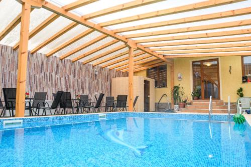 einen Pool mit einer hölzernen Pergola sowie Tischen und Stühlen in der Unterkunft Hotel Saint Nicola in Banya