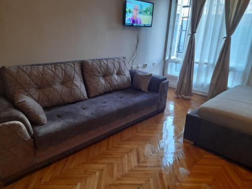 ein Wohnzimmer mit einem Sofa und einem TV an der Wand in der Unterkunft Mario Sunce Apartmani in Niš