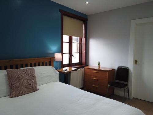 1 dormitorio con cama, escritorio y ventana en The Orchard Hotel, en Falkirk