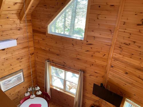 Habitación con paredes de madera y ventanas en una cabaña de madera. en Avonlea Forest Hill Cottages, en New Glasgow