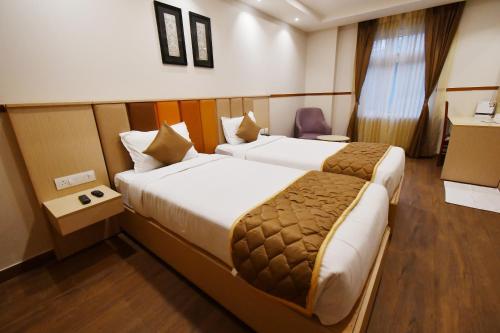 een hotelkamer met 2 bedden en een stoel bij Soho Boutique Hotel in Mysore