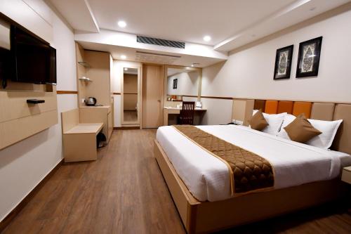 een hotelkamer met een groot bed en een televisie bij Soho Boutique Hotel in Mysore