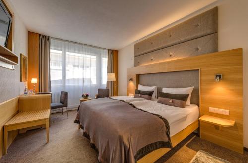 ein Hotelzimmer mit einem großen Bett und einem Schreibtisch in der Unterkunft Continental Hotel Lausanne in Lausanne