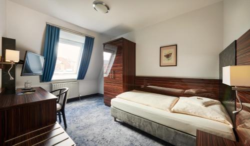 a bedroom with a bed and a desk and a television at Stadthotel am Wasen in Stuttgart