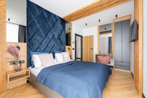 een slaapkamer met een groot bed met een blauw hoofdeinde bij Wrota Chałubińskiego in Zakopane