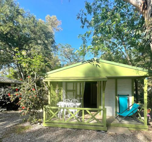 um barracão verde e branco com uma mesa e cadeiras em Camping la Clé des Champs em Calvi