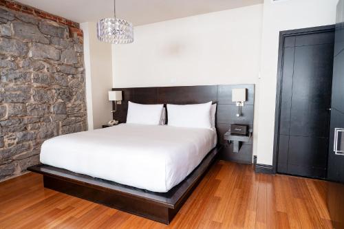 um quarto com uma cama branca e uma parede de tijolos em Le Petit Hôtel Vieux-Montréal - Saint-Paul by Gray Collection em Montréal