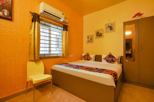 1 dormitorio con cama, ventana y silla en FabHotel Vijaylakshmi Stay Inn - Nr Meenambakkam Metro Station, en Chennai