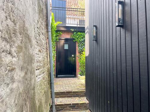 um corredor com uma porta preta num edifício em B&B 't Gasthuysje em Dokkum