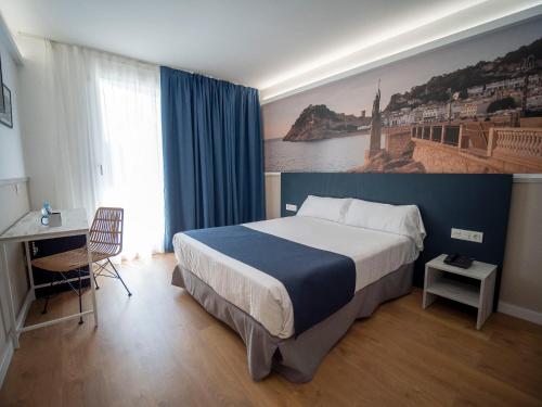 ein Hotelzimmer mit einem großen Bett und einem Schreibtisch in der Unterkunft Hotel Don Juan Tossa in Tossa de Mar