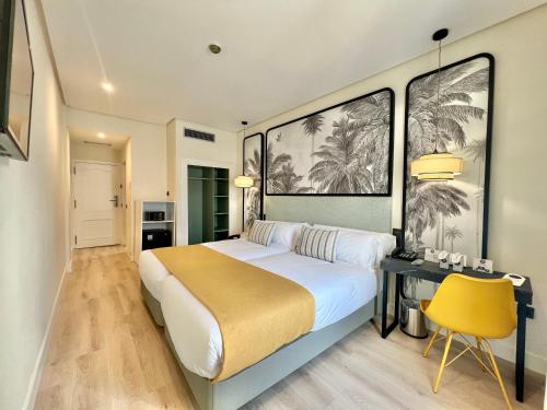 een slaapkamer met een groot bed en een gele stoel bij Soho Boutique Puerto in El Puerto de Santa María