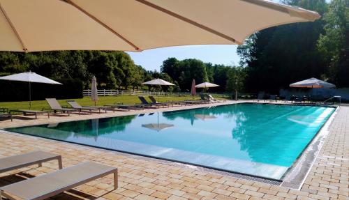 a large swimming pool with chairs and umbrellas at Gut Drasing in Krumpendorf am Wörthersee