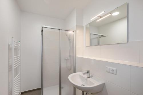 La salle de bains blanche est pourvue d'un lavabo et d'une douche. dans l'établissement Hostel Am Windberg, à Freital