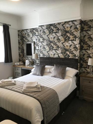 een slaapkamer met een groot bed met bloemenbehang bij The Kenmore Guest House in Llandudno