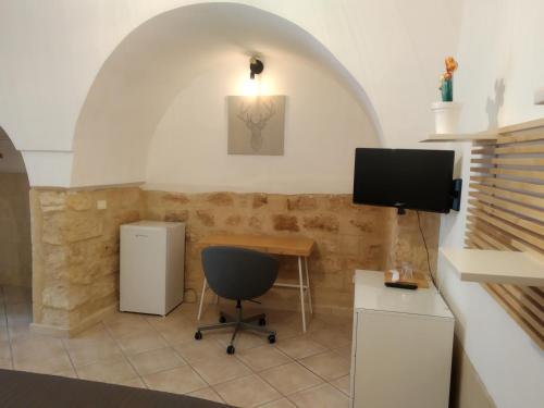 Habitación con escritorio, TV y silla. en Dimora Dioniso, en Polignano a Mare