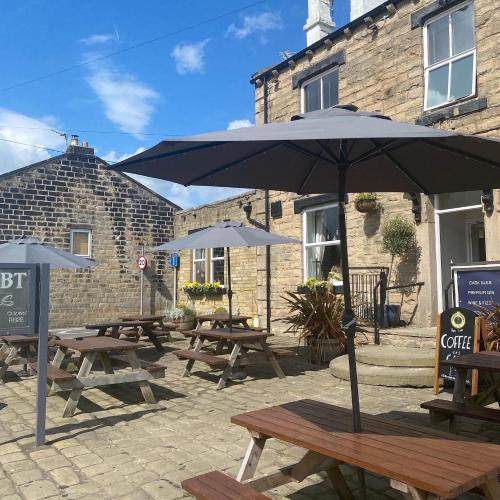 a group of picnic tables with umbrellas in front of a building at The White Swan, Yeadon in Yeadon