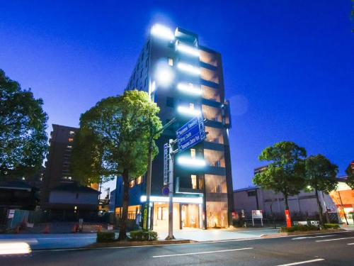 un edificio alto con letreros de la calle azul delante de él en HOTEL LiVEMAX Himeji Shiyakusho Mae, en Himeji