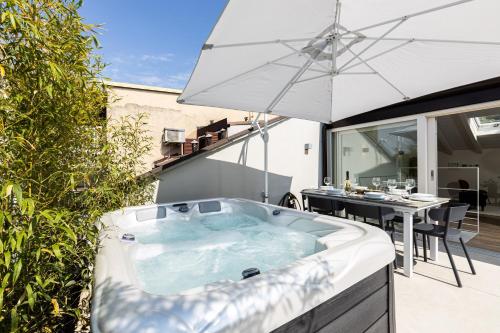 een hot tub op een patio met een parasol bij *Villa Olivo*with private terrace & Jacuzzi + 3bedrooms in Milaan