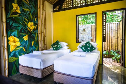 2 Betten in einem Zimmer mit Wandgemälde in der Unterkunft Fox & The Firefly Cottages in Loboc