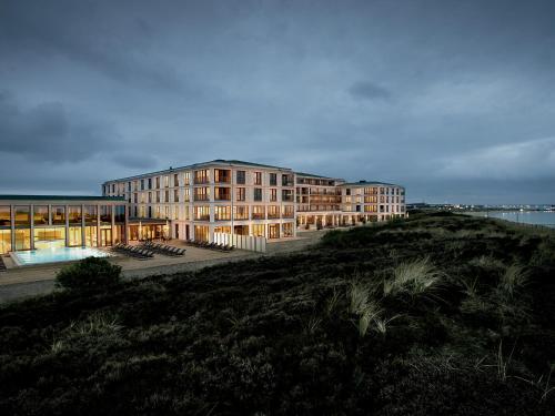 ein Gebäude auf einem Hügel neben einem Wasserkörper in der Unterkunft A-ROSA Sylt in List