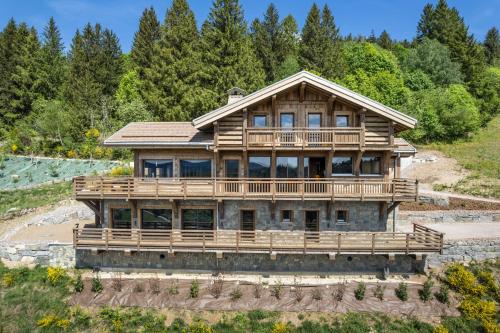 a large wooden house on a hill with trees at Aigle des Neiges 5 étoiles in Gérardmer