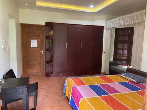 - une chambre avec un lit coloré et un bureau dans l'établissement Maleyam Homestay Riverside, à Kozhikode