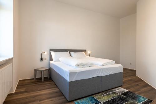 - une chambre avec un grand lit et des draps blancs dans l'établissement City Apartments Amstetten, à Amstetten