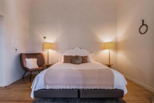 een slaapkamer met een bed met 2 lampen en een stoel bij Templo Boutique Hotel in Évora