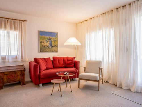 - un salon avec un canapé rouge et une chaise dans l'établissement Apartment Chesa Pra d`Sura 217-10 by Interhome, à Maloja