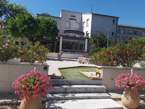 un edificio con escaleras y flores en jarrones en Hôtel Restaurant Le Clos Charmant, en Vallon-Pont-dʼArc