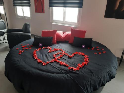 Una cama con un corazón hecho de rosas rojas en Ds Plaisir Love Room avec sauna, jacuzzi à Nancy, en Nancy