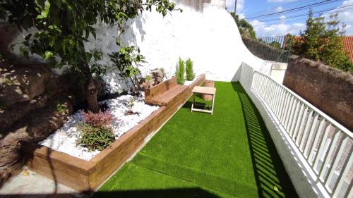 un petit jardin avec un banc et de la pelouse dans l'établissement Lemon Tree House Coimbra - Courtyard garden with city views, à Coimbra