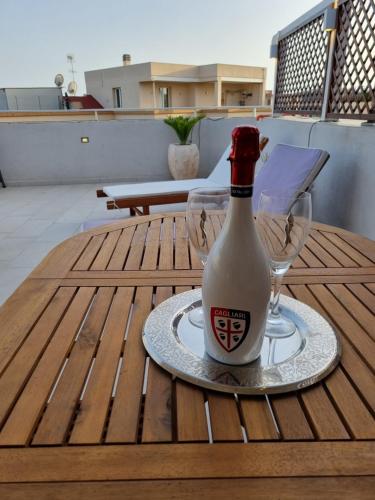 uma garrafa de vinho e dois copos numa mesa em Nuovo attico con terrazza 5 minuti dal mare em Cagliari