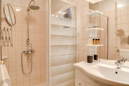 y baño blanco con lavabo y ducha. en Isida, Maison spacieuse avec terrasse et stationnement, en Caen