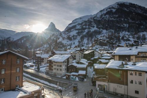 a town with snow covered buildings in front of a mountain at Hotel Parnass in Zermatt