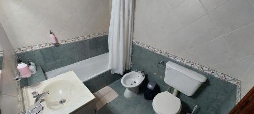 a bathroom with a white toilet and a sink at Casa de La Lila in Salta