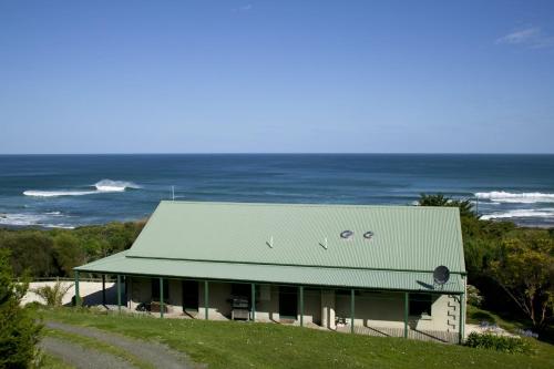 ein Haus mit grünem Dach und Meer in der Unterkunft Bennetts Beach House in Apollo Bay