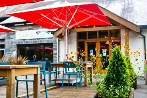 un ristorante con tavoli e sedie e un ombrellone rosso di The Waterloo Hotel a Betws-y-coed