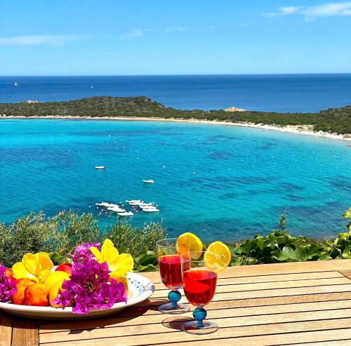 een tafel met een schaal fruit en wijnglazen bij SAN TEODORO PUNTA EST SPETTACOLARE QUADRILOCALE VISTA MARE in Capo Coda Cavallo