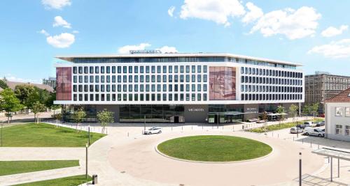 un grand immeuble de bureaux avec un parc en face de celui-ci dans l'établissement V8 HOTEL Motorworld Region Stuttgart, à Böblingen