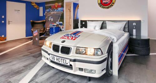 - une chambre avec un lit avec une voiture de course dans l'établissement V8 HOTEL Motorworld Region Stuttgart, à Böblingen