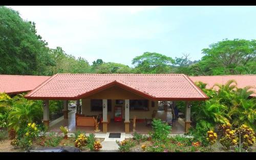 een klein huis met een rood dak en een aantal planten bij Hotel D'Lucia - Quebrada Ganado, Jaco, Costa Rica in Puntarenas