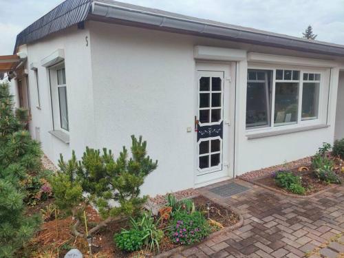 a white house with a door and some plants at Ferienwohnung in Leckwitz bei Nünchritz Wacker, Elbradweg in Nünchritz