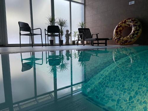 a swimming pool with chairs and a reflection in the water at Nidos kempingas in Nida