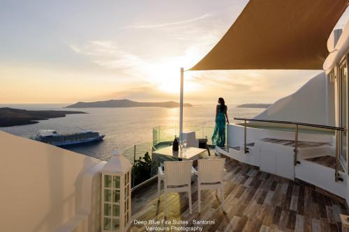 une femme debout sur un balcon donnant sur l'océan dans l'établissement Fira Deep Blue Suites, à Fira