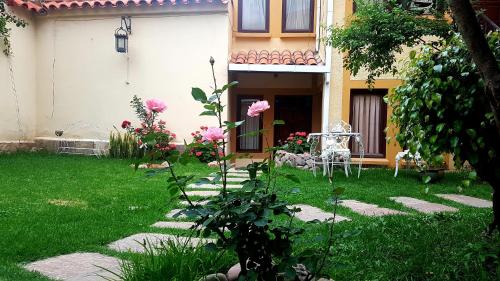 um jardim em frente a uma casa com rosas rosas em Paola Hostal em Sucre