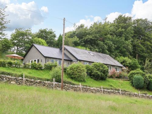 uma casa numa colina com uma cerca de pedra em Ochr Y Garth em Llanrwst