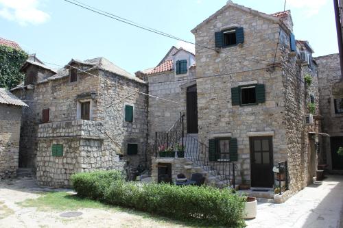 una antigua casa de piedra con una escalera en una calle en Stone house Castellum, en Kaštela