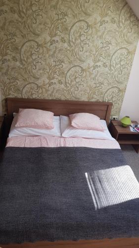 a bed with two pillows and a wall at Végvár Delux apartman in Gyula