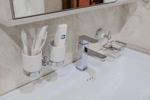 a bathroom sink with toothbrushes in cups on it at Guest House Diyor Gold in Samarkand